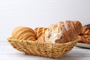 Different pastries in basket on white wooden table