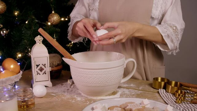 Baker breaks an egg and adds it to bowl for making a variety of Christmas pastries, including cakes, pies, and ginger cookies.