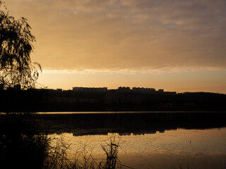 Warm hues of sunset illuminate the sky while casting reflections on the tranquil surface of the...