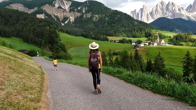 Tourist holding her hat while admiring the odle mountains and santa maddalena church in val di funes