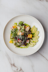 Colorful salad with grilled chicken, creamy avocado, sweet mango, crispy croutons, and parmesan, topped with dressing and presented on a white plate. Restaurant or cafe menu, cookbook recipe

