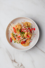 Delicious crispy fried shrimp topped with delicate rice noodles, fresh green onions, spicy red chili peppers, and tobiko flying fish roe. Restaurant or cafe menu, cookbook recipe
