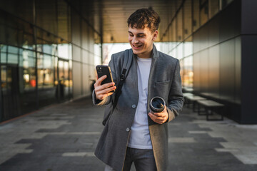 young man drink coffee walk from work and have video call on cellphone