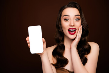 Photo of surprised glamour girl showing empty space screen gadget isolated on brown color background