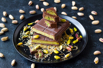Sliced ​​Dubai Chocolate, with pistachios and kunefe pieces piled on a black plate