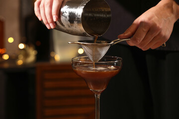 Bartender making delicious espresso martini in bar, closeup