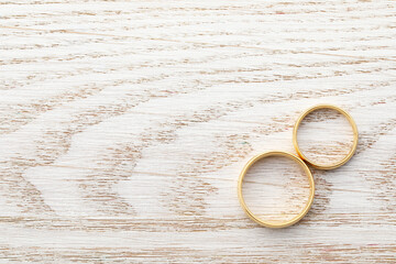 Beautiful golden wedding rings on wooden table, top view. Space for text