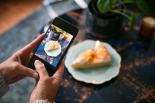 Woman taking photo of birthday cake with smartphone