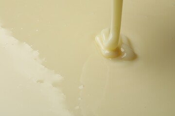 Pouring delicious condensed milk as background, closeup