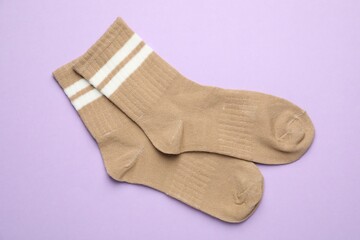 Pair of soft socks on violet background, top view