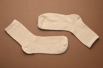 Pair of soft socks on light brown background, top view