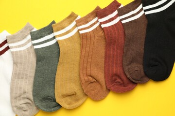 Different soft socks on yellow background, flat lay