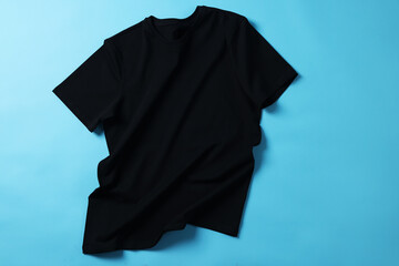 One black t-shirt on light blue background, top view