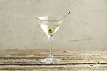 Martini cocktail with olive in glass on wooden table