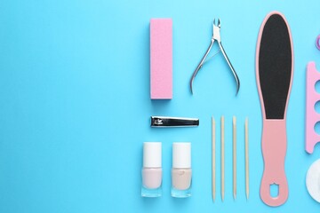 Set of pedicure tools on light blue background, flat lay. Space for text
