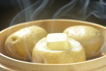 湯気が立ち昇る蒸籠でじゃがバター調理する