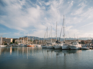 Sailboats and motorboats docked at Palermo marina with historic buildings