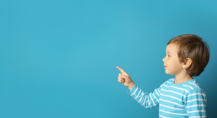 Young boy pointing at something on blue background