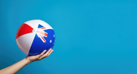 Naklejka premium Hand holding beach ball with geometric design on blue background