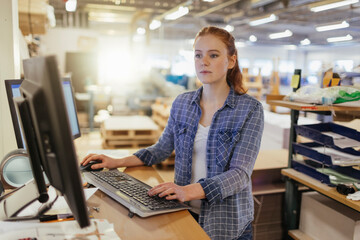 Woman working on computer in printing warehouse