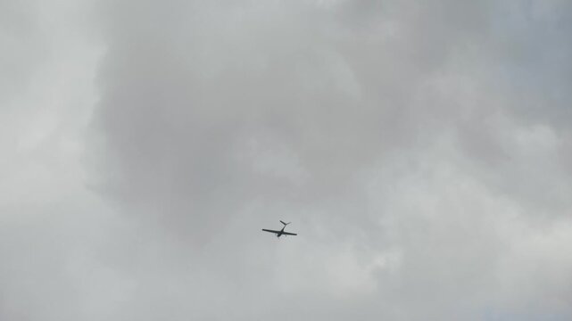 Aircraft with V-tail control surfaces is soaring gracefully through overcast skies. V-shaped configuration tail airplane, showcasing its striking silhouette against a moody backdrop with clouds
