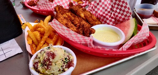 A tray with a basket of chicken tenders with fries