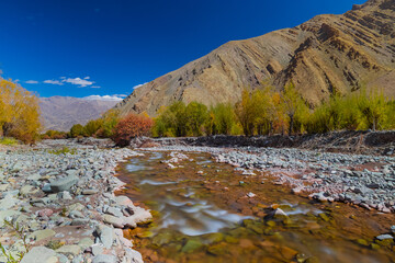 Fototapeta premium Long exposure of water flowing downstream from mountain during autumn season.