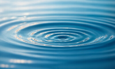 A single water droplet creates concentric ripples on a serene blue surface, capturing the elegance of motion and the tranquility of nature. This image symbolizes simplicity, purity, and the ripple eff