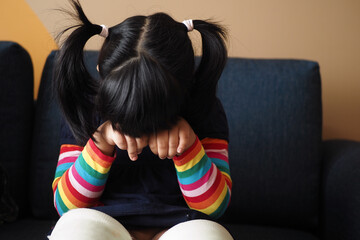 a upset child girl cover her face with hand 