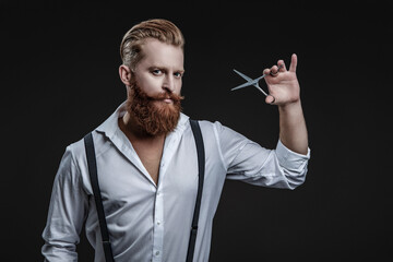 Haircut from a hairstylist at a barbershop. Bearded Caucasian man hairdresser in hair salon. Hairstylist working in a hair salon. Barber using scissors isolated on black