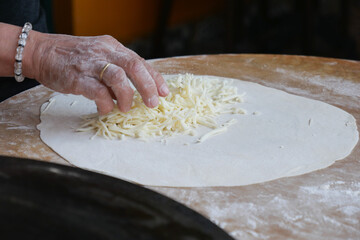 Cheese Being Added to Dough for the Preparation of a Delicious Dish