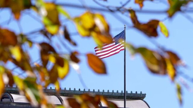 Tripod shot of an American flag blowing in the wind ontop of a building
