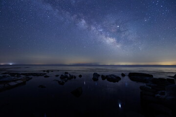 星が水面にゆれている海辺と天の川と能登半島の星空