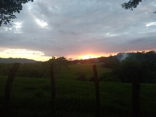 sunset colors on the horizon with sky full of clouds and wooden fence in the foreground