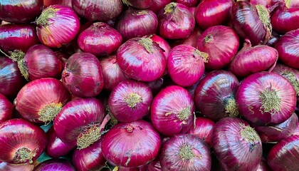 A vibrant pile of red onions, showcasing their rich color and natural texture.