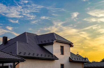 General view of houses with metal tile roofs against the background of the cityscape