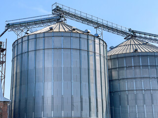 Huge metal silos for storing grain against the background of the blue sky