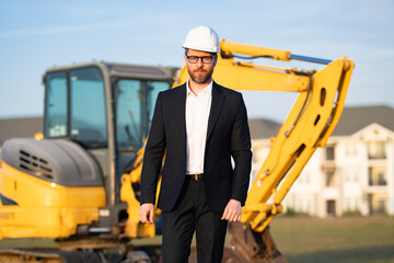 Civil engineer worker at a construction site. Engineer man in front of house background. Confident engineer worker at modern home building construction. Hispanic civil engineer in helmet.