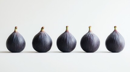 Obraz premium Fresh figs arranged in a line against a minimalistic white background showcasing their rich color and unique shape for culinary themes.