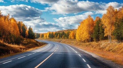 Fototapeta premium Winding highway through vibrant autumn foliage under a clear blue sky in a serene landscape setting