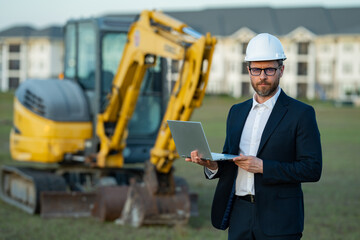 Architect at a construction site. Architect man in helmet and suit at modern home building...