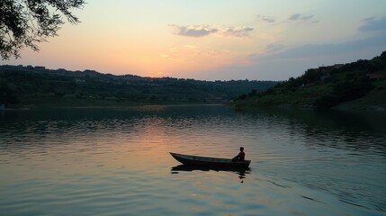 Obraz premium A serene sunset scene with a lone person in a boat on a tranquil lake.