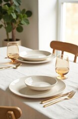 A beautifully arranged table displays minimalist dishware and elegant glassware in a well-lit, inviting setting