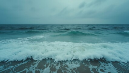 Fototapeta premium Serene Ocean Waves Crashing on Shore Under an Overcast Sky, Wide Shot Seascape Photography