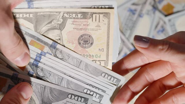 From a large stack of hundred-dollar bills, only a single ten-dollar note is handed over, highlighting value disparity or minimal reward.