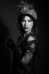 Black and white studio portrait of a caucasian woman dressed in 1920's fashion flapper outfit. She...