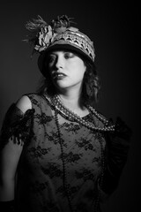 Black and white studio portrait of a caucasian woman dressed in 1920's fashion flapper outfit. She...