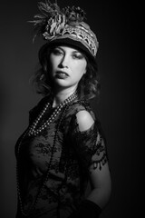 Black and white studio portrait of a caucasian woman dressed in 1920's fashion flapper outfit. She...