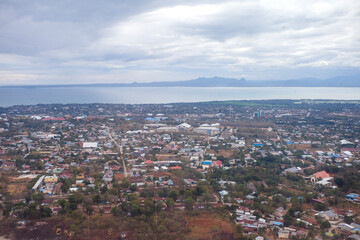 Aerial view of Kupang city, the capital of East Nusa Tenggara Province, Indonesia. Urban landscape with coastline, settlements, built-up areas and some agricultural areas.