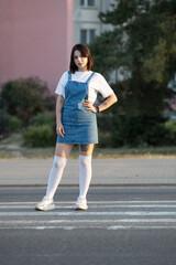 Portrait of a young beautiful dark-haired girl in a denim sundress outdoors.